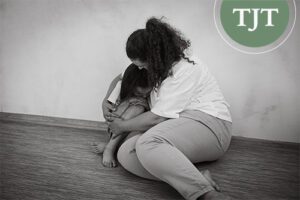 Foster mother comforting a young girl sitting on the floor